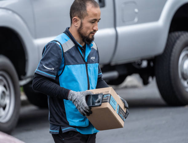 Amazon.com Delivery Person with Package Berks County, Pennsylvania, USA, April 26, 2020-Amazon.com delivery person wearing gloves packages on suburban street amazon.com photos stock pictures, royalty-free photos & images