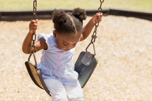cute little african american kołysząc się w parku. - child swinging playground african descent zdjęcia i obrazy z banku zdjęć