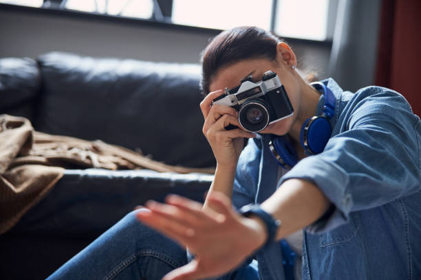 istock Female photographer in denim clothes using camera at home 1221486532
