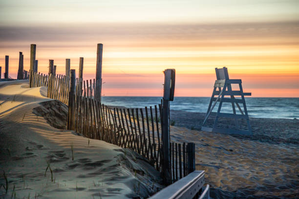 Empty beach at Beach Haven, NJ at sunrise An empty lifeguard stand and a dune fence greet the colorful dawn sky on the beach beach hut photos stock pictures, royalty-free photos & images