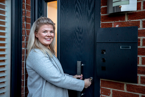 Young caucasian woman opening the door to her new home and smiling.