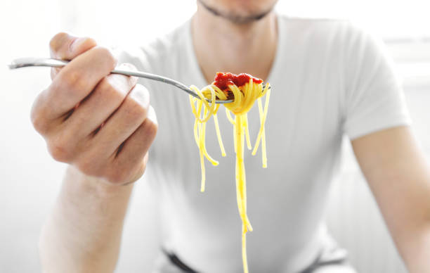 istock Man eating tasty spaghetti with tomato sauce 1221490279