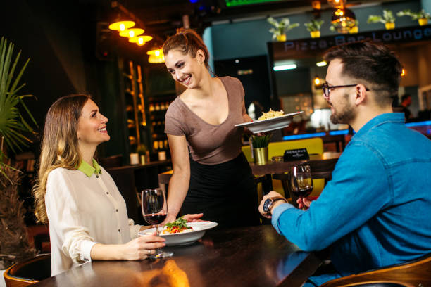 istock Young waitress serving young couple at the restaurant 1221493930