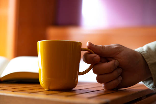 istock Hand picking up a yellow cup of coffee at home. 1221497695