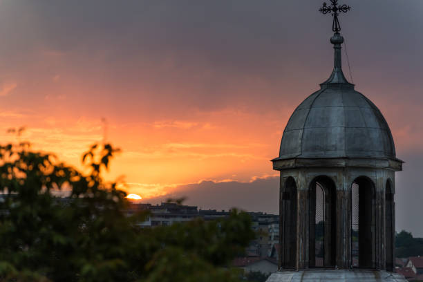 Red/ orange sunset over a town and orthodox church