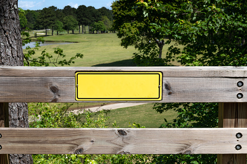 Close view of wooden fence with blank yellow sign ready for your text, creative copy space, horizontal aspect