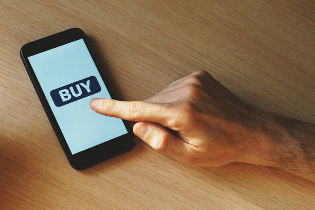istock Hand and smartphone with a button Buy. 1221501055