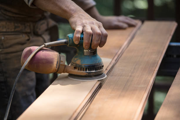 istock Man sanding redwood planks outdoors with orbital sander 1221501303