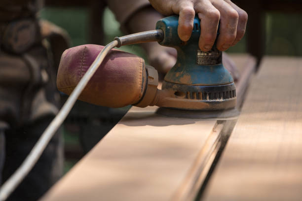 istock Man sanding redwood planks outdoors with orbital sander 1221501316