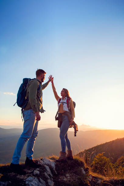 istock Couple on Top of a Mountain Shaking Raised Hands 1221501321