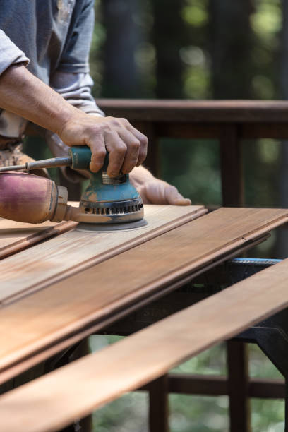 istock Man sanding redwood planks outdoors with orbital sander 1221501344