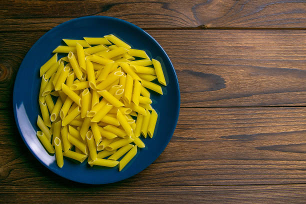 Pene Lisce pasta in blue plate on dark wooden background. Top views with clear space