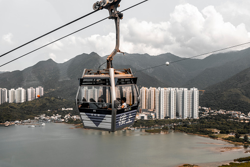 Tourists in the Ngong Ping 360 Skyrail cable car above Tung Chung Bay. Yat Tung Estate behind them.
