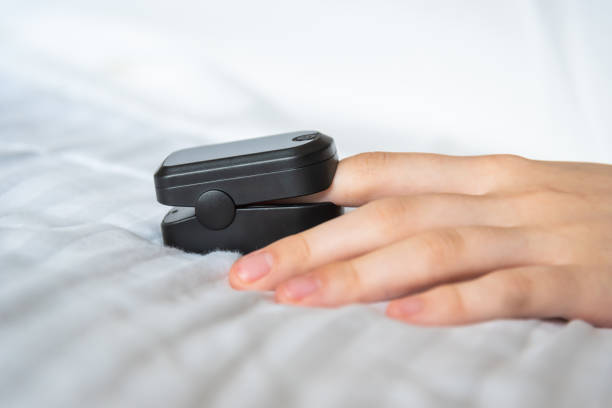 close-up of pulse oximeter on woman's finger with white sheet and copy space - taking pulse oximeter medical oxygen equipment human lung imagens e fotografias de stock