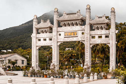 Tourists sightseeing next to huge gate to Po Lin Monastery, Lantau Island, Hong Kong.