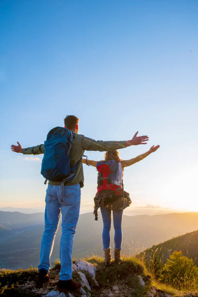 istock Couple with raised arms holding hands and looking at sunset 1221504450