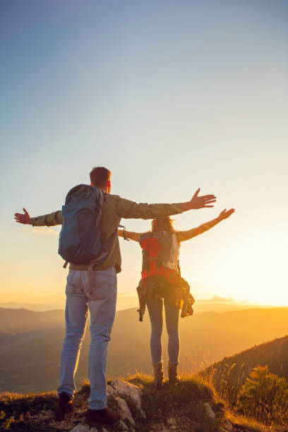 istock Couple with raised arms holding hands and looking at sunset 1221506092
