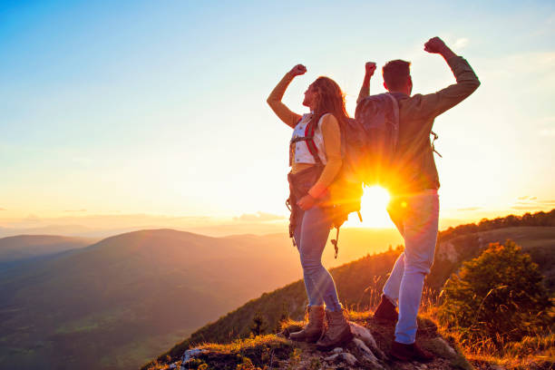 istock Couple on Top of a Mountain Shaking Raised Hands 1221506887