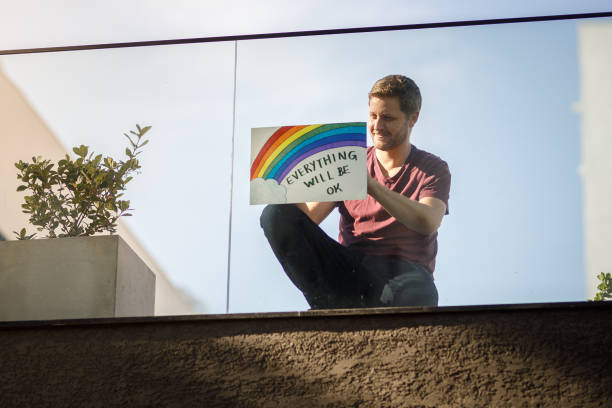 istock Man hanging up a poster with hope message against covid-19 1221506912