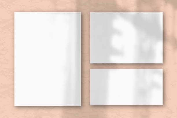 istock Several horizontal and vertical sheets of white textured paper on the background of a pink wall. Natural light casts shadows from the window. Flat lay, top view 1221506963