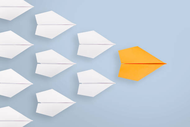 istock Leadership concepts with Orange paper airplane leading among white 1221507736