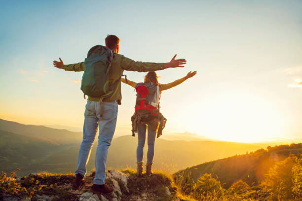 istock Couple with raised arms holding hands and looking at sunset 1221507868