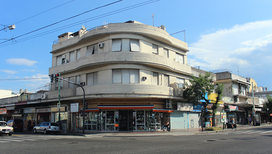 Small building in a corner of a road intersection of a commercial neighborhood, with closed shops on the ground floor (West of the city of Buenos Aires, Argentina)