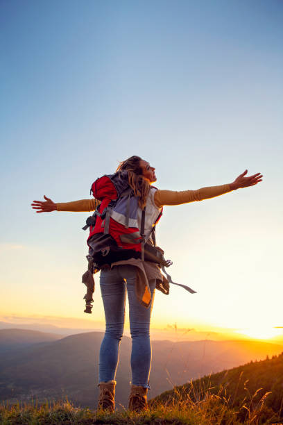 istock cheering woman hiker open arms at mountain peak 1221508726