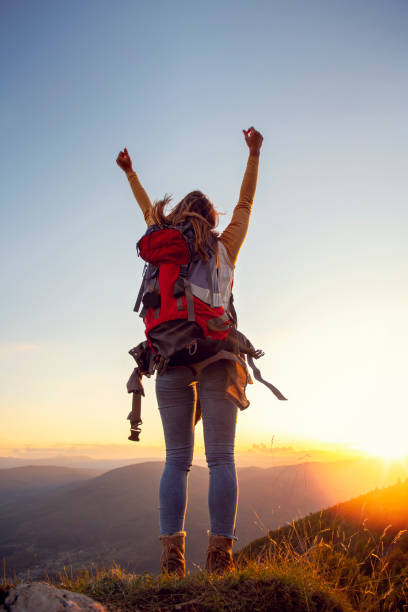istock cheering woman hiker open arms at mountain peak 1221508936