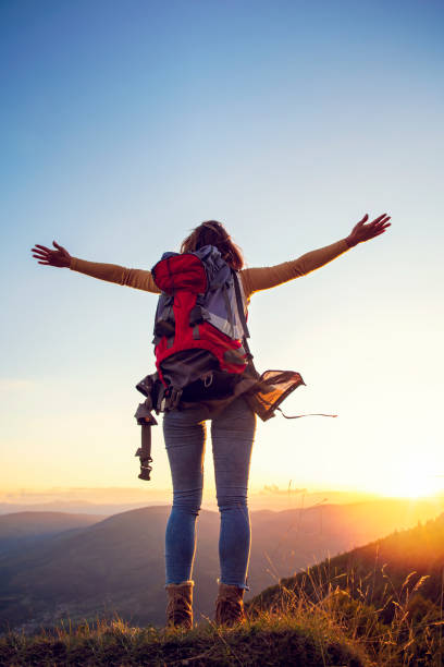 istock cheering woman hiker open arms at mountain peak 1221512104