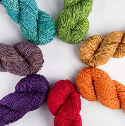 A rainbow of woolen yarn hanks arranged in a circle