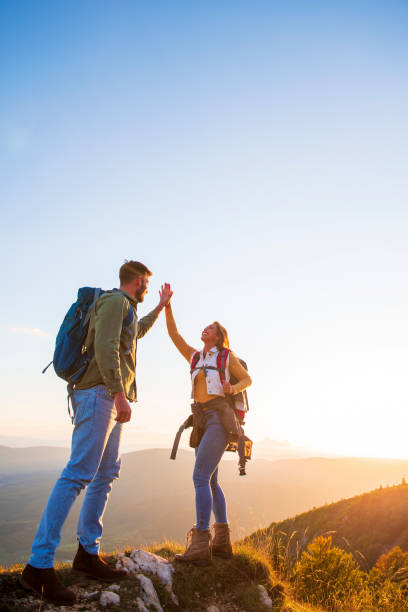 istock Couple on Top of a Mountain Shaking Raised Hands 1221512189