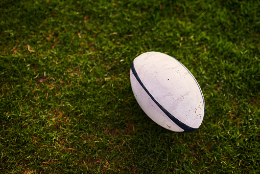 Cropped shot of a rugby ball on an empty rugby field during the early hours of the morning