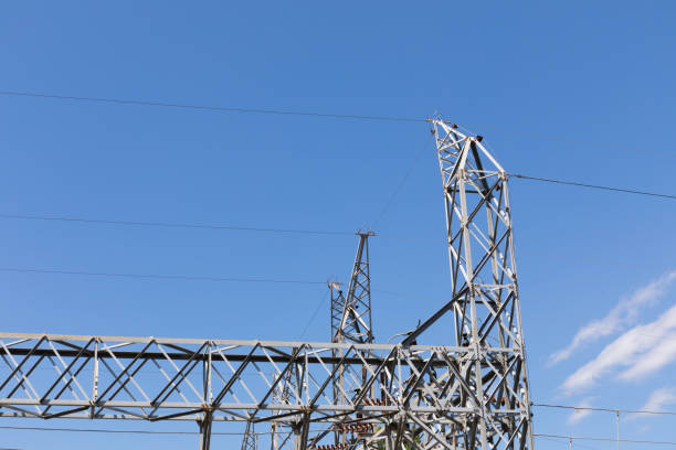 istock Metal trusses supporting electrical wires and insulators viewed from below, blue sky with clouds 1221513021