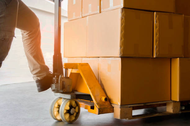 istock Warehouse worker with hand pallet truck and package boxes on pallet 1221519392
