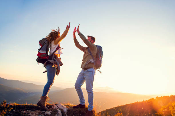 istock Couple on Top of a Mountain Shaking Raised Hands 1221521476