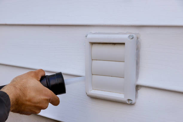 istock Applying silicone on exhaust fan on the wall outside siding trim 1221522238