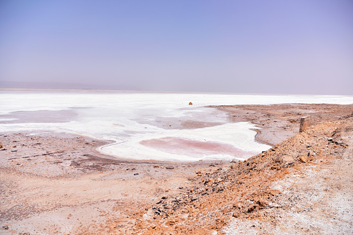 DEGUECHE, TN - JULY, 2019: Chott el Djerid, also spelled Sciott Gerid and Shott el Jerid, is a large endorheic salt lake in southern Tunisia. Endorheic salt lake with shallow pool of salty water and an S-shaped crust of crystalized salt.