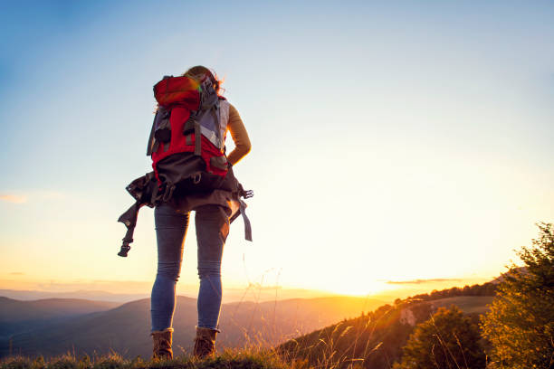 istock cheering woman hiker open arms at mountain peak 1221523326