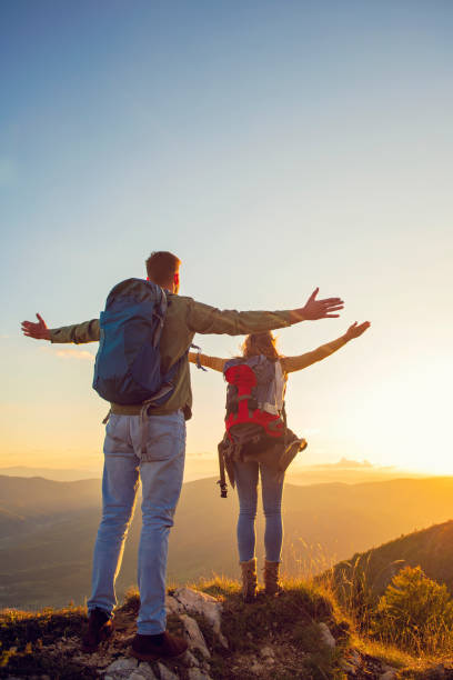 istock Couple with raised arms holding hands and looking at sunset 1221527243