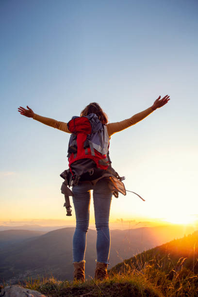 istock cheering woman hiker open arms at mountain peak 1221529225