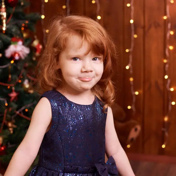 Beautiful little girl. Blue dress. Christmas interior.