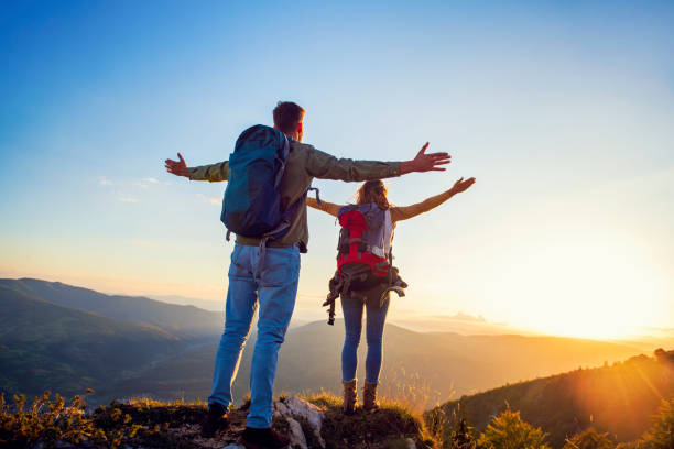 istock Couple with raised arms holding hands and looking at sunset 1221529448