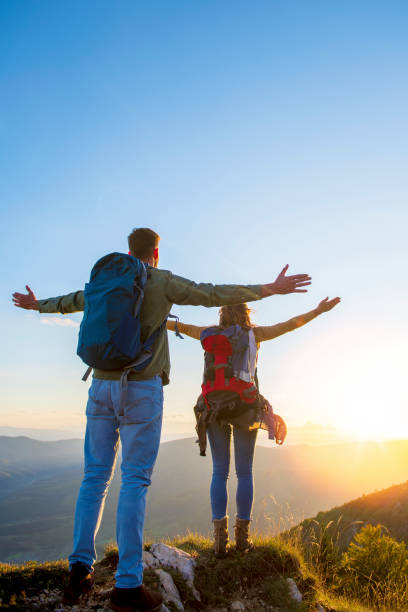 istock Couple with raised arms holding hands and looking at sunset 1221529566