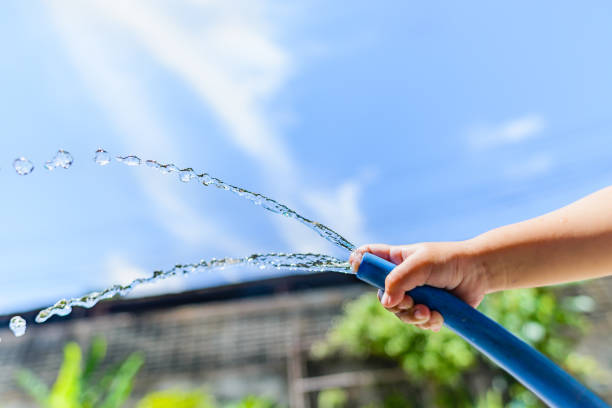 Water hose with sream of water coming out againest a green background