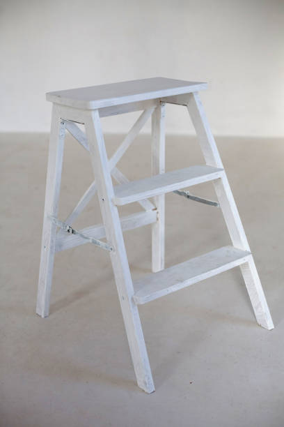 istock Wooden ladder in white room. White wall 1221536757