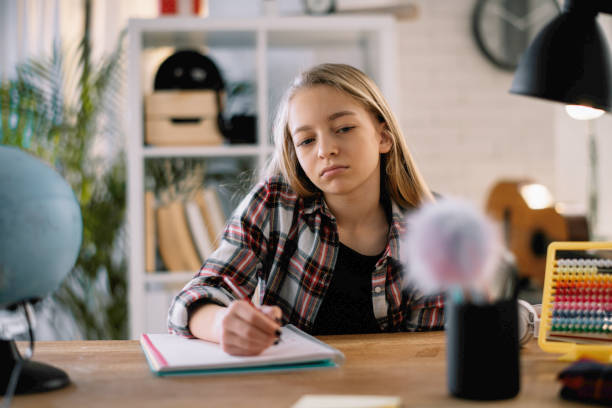 istock Beautiful little girl doing homework at home. 1221536982