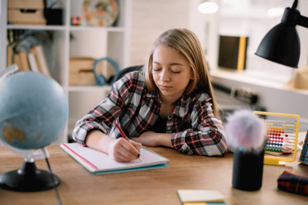 istock Beautiful little girl doing homework at home. 1221536994