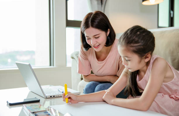 istock mother working at  home and help daughter doing home work 1221537077