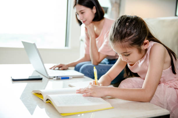 istock mother working at  home and help daughter doing home work 1221537083